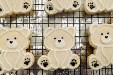polar bear cookies on a wire rack over an aluminum foil lined baking sheet