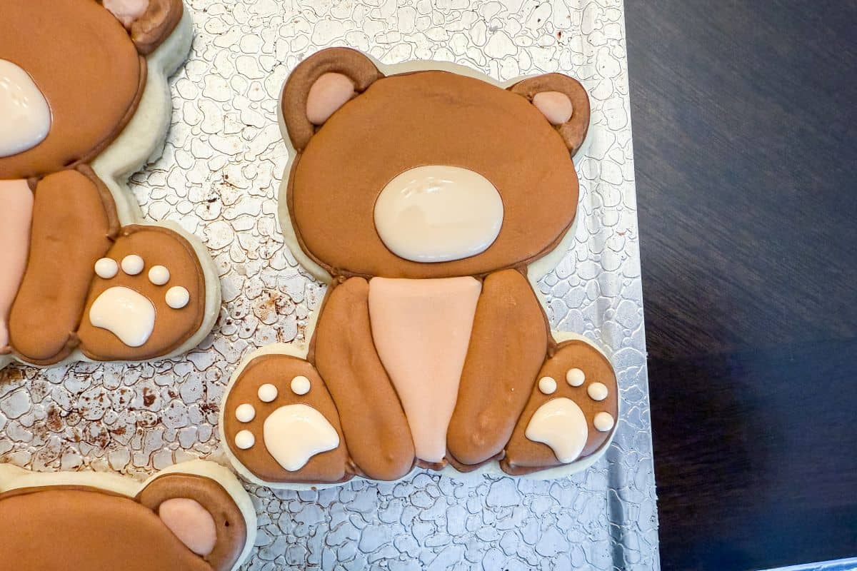 royal icing teddy bear cookies with snout and paw sections filled but without final details