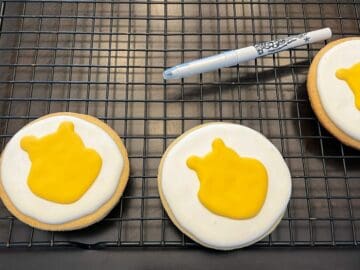 yellow royal icing in the shape of Winnie the Pooh's face on a white cookie