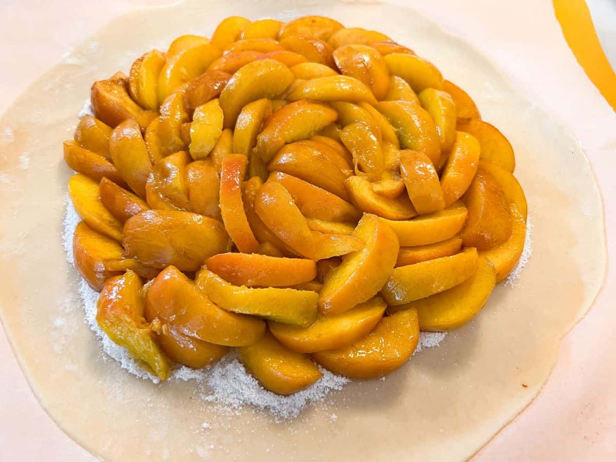 slices of peaches arranged in a circular pattern on top of pie crust