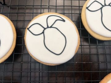 black royal icing outline of piglet's face and ears on a white royal icing cookie