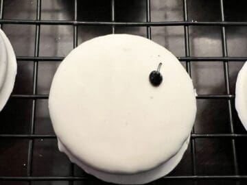 black dot of royal icing on a white fudge covered Oreo