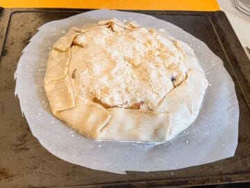 an assembled tart on a parchment lined baking sheet before baking