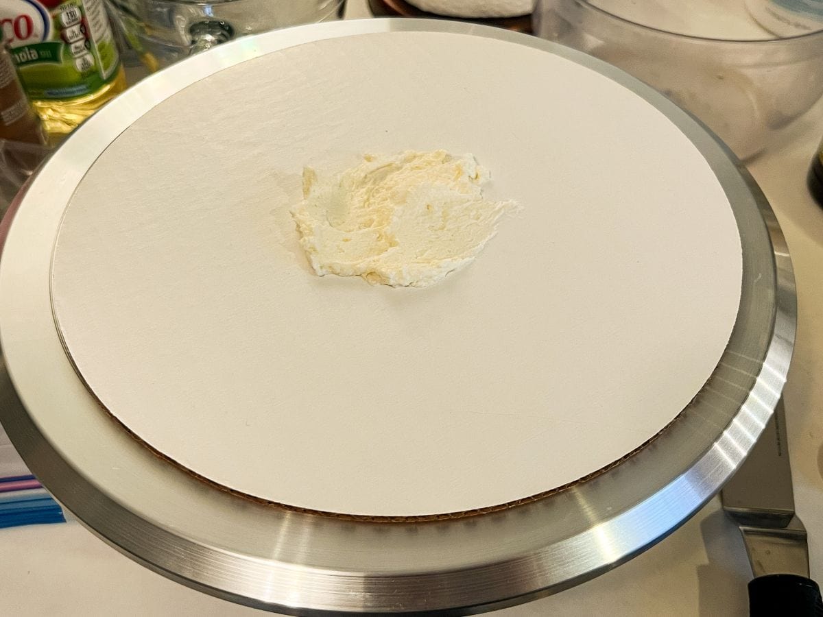 a smear of cream cheese frosting on a round cardboard cake board