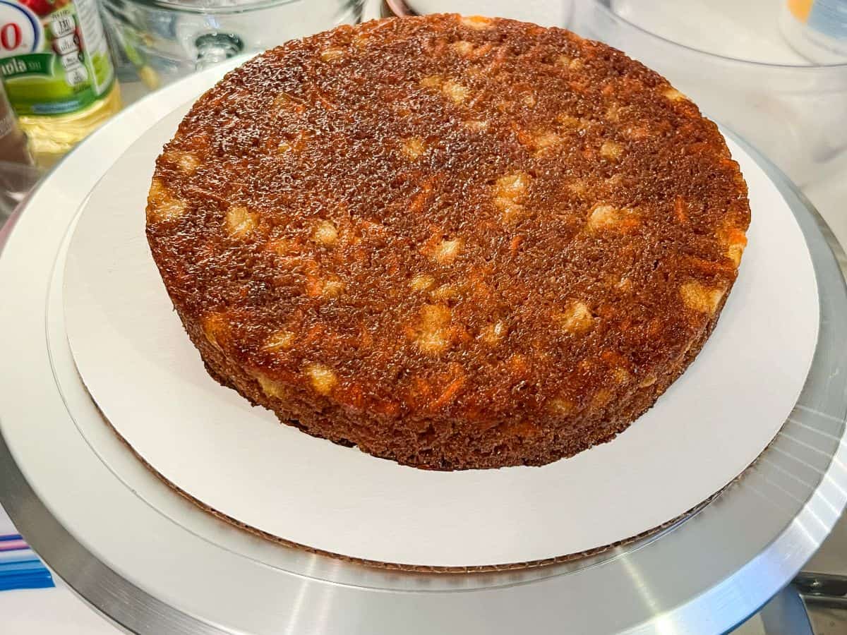 a round carrot cake on top of a cardboard cake board