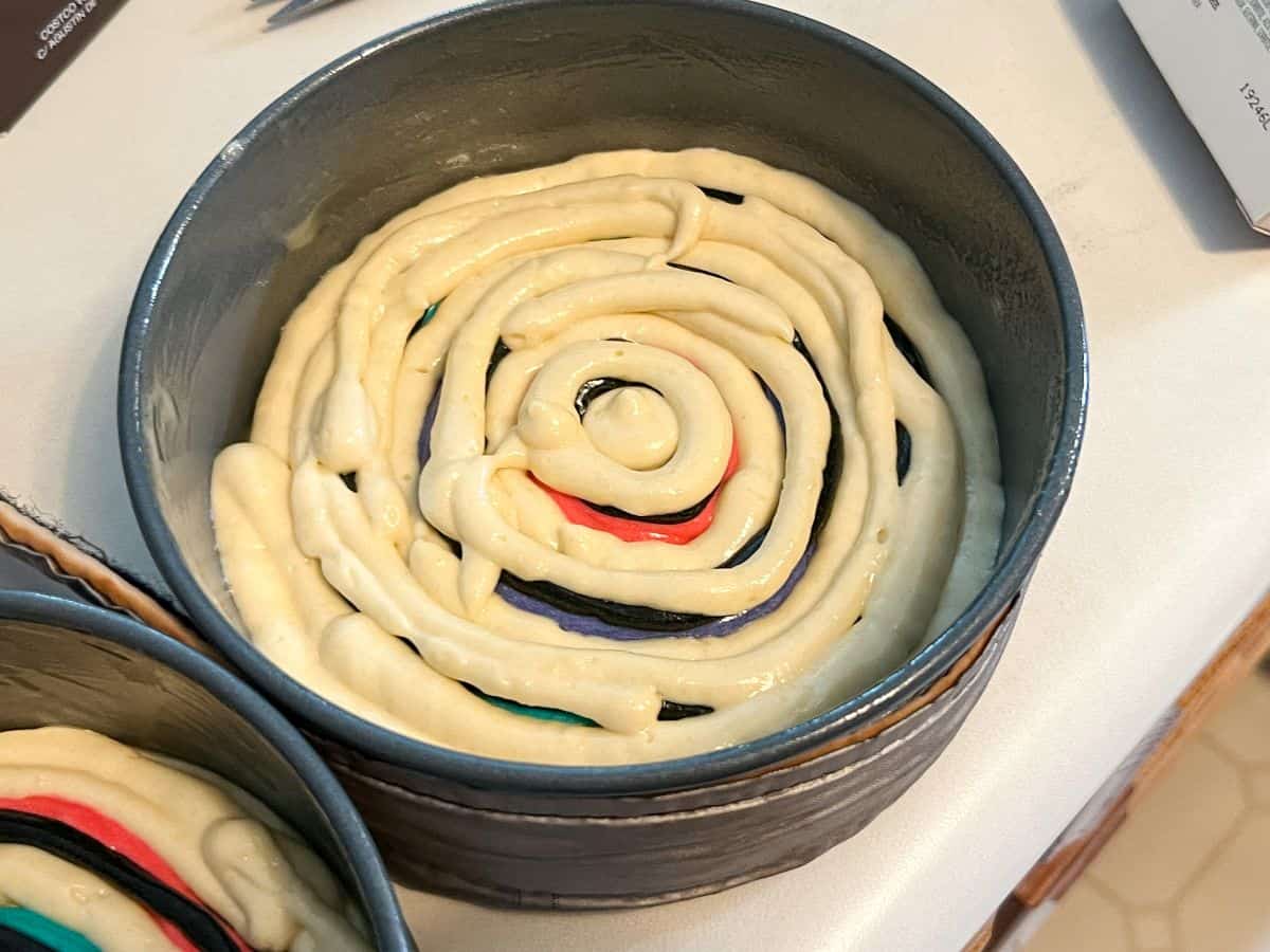 untinted cake batter piped between colors in round cake pan