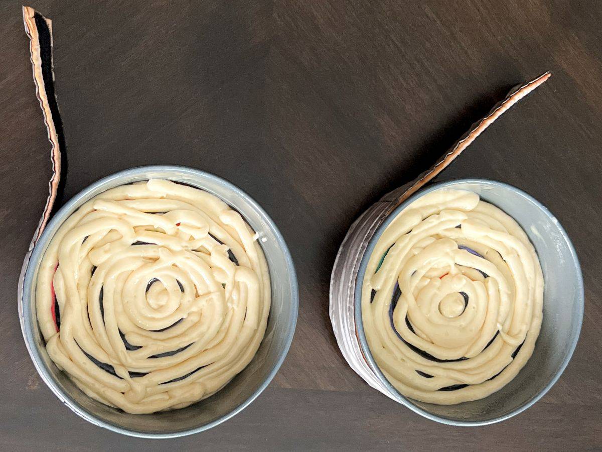 two round cake pans with colored batter covered by untinted batter