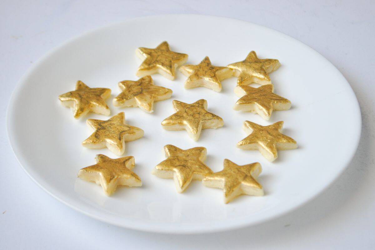 gold painted cookies shaped like stars on a white plate