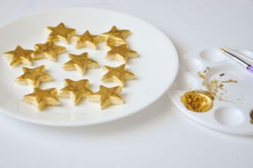 a plate of gold painted cookies next to a paint palette