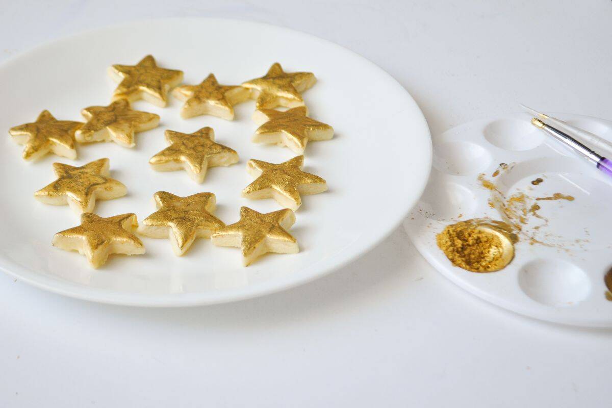 a plate of gold painted cookies next to a paint palette