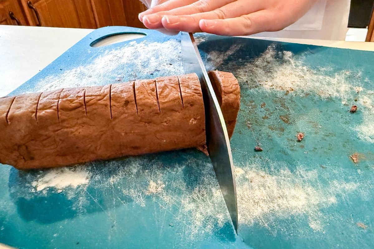 a knife slicing through a log of chocolate cookie dough