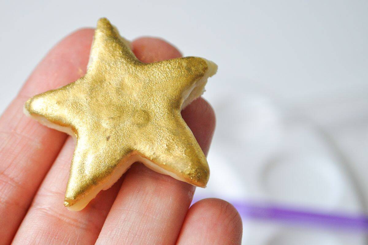 a gold painted cookie shaped like a star being held up
