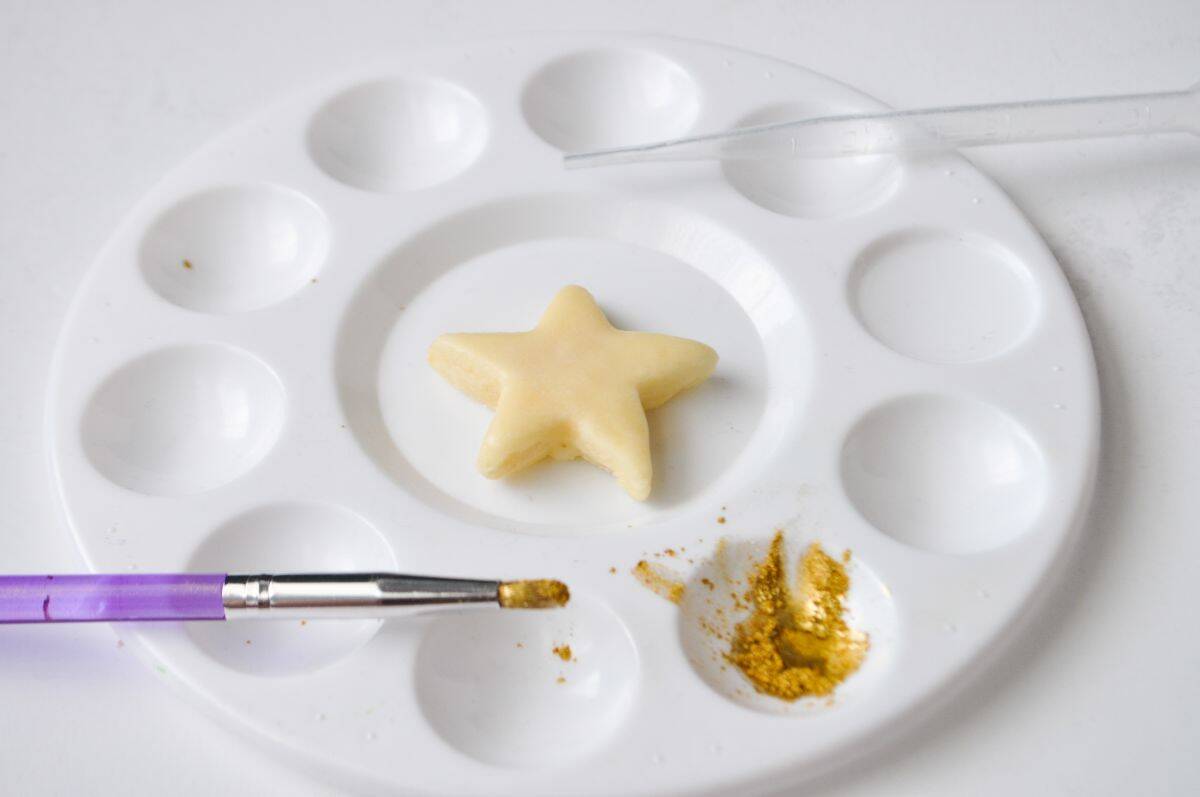 gold luster dust in the well of a paint palette with an iced cookie in the center