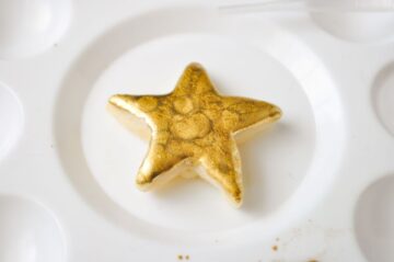 a gold painted cookie in the center of a paint palette