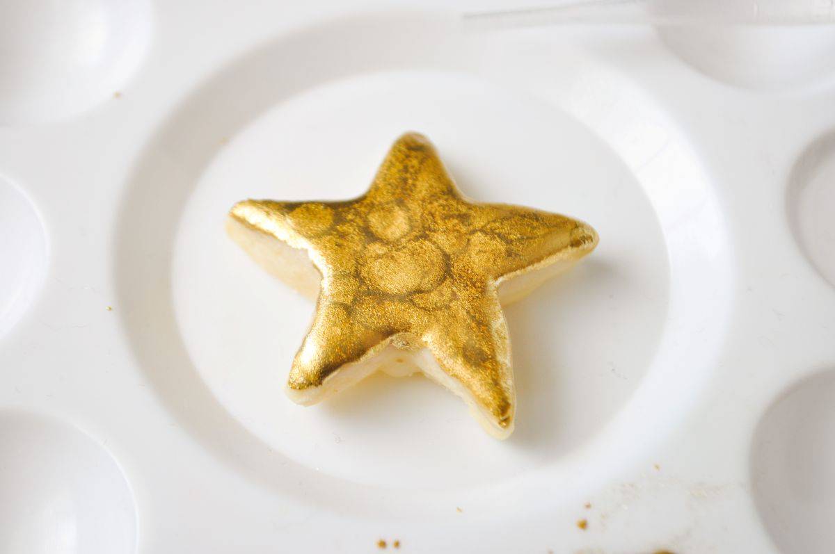 a gold painted cookie in the center of a paint palette