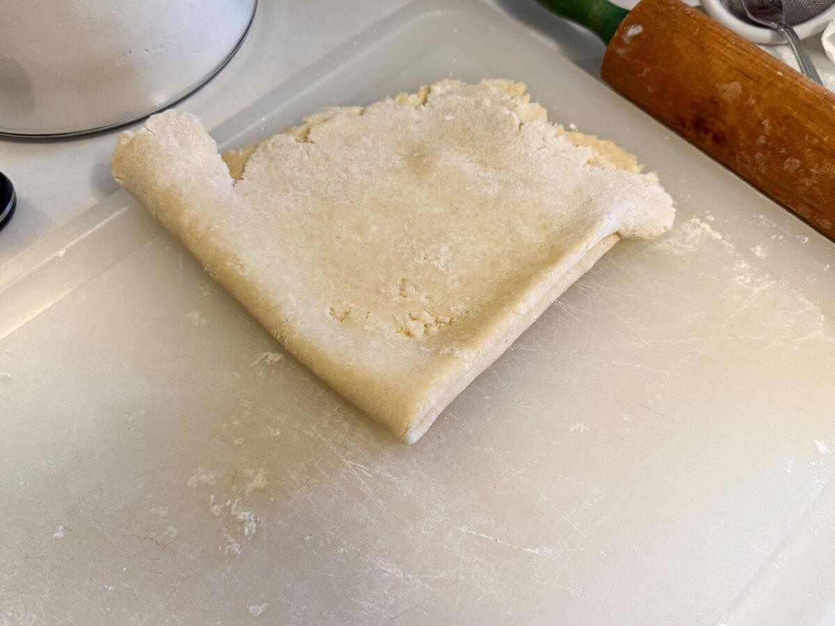 pie dough folded into fourths on a floured cutting board