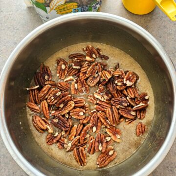 pecans dumped into a bowl of pecan pie filling