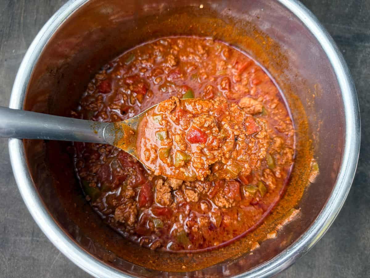 a metal spoon lifting up low carb turkey chili out of an instant pot