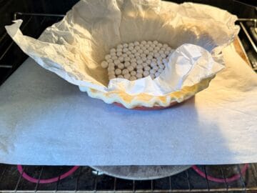 a single crust pie filled with parchment paper and pie weights in an oven