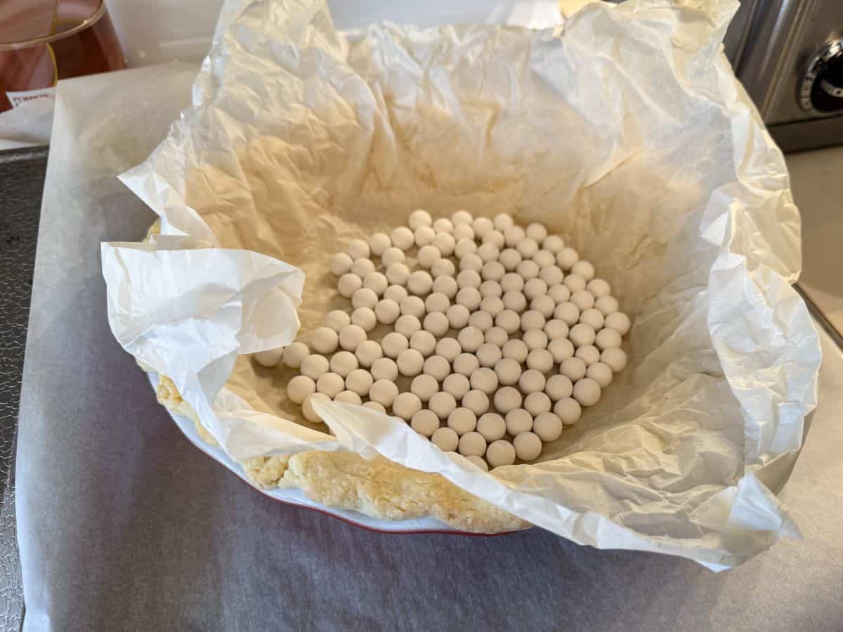 a single crust pie with parchment inside filled with pie weights