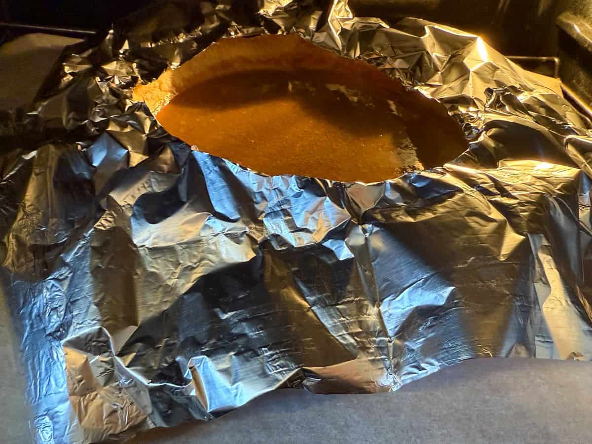 a pumpkin pie with aluminum foil around the edges of the crust to prevent over-browning