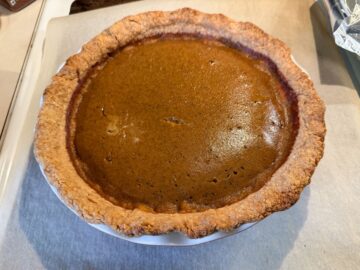 a baked pumpkin pie cooling on a stovetop