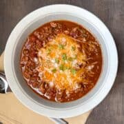 a bowl of Low Carb Turkey Chili with cheese and chopped green onions on top