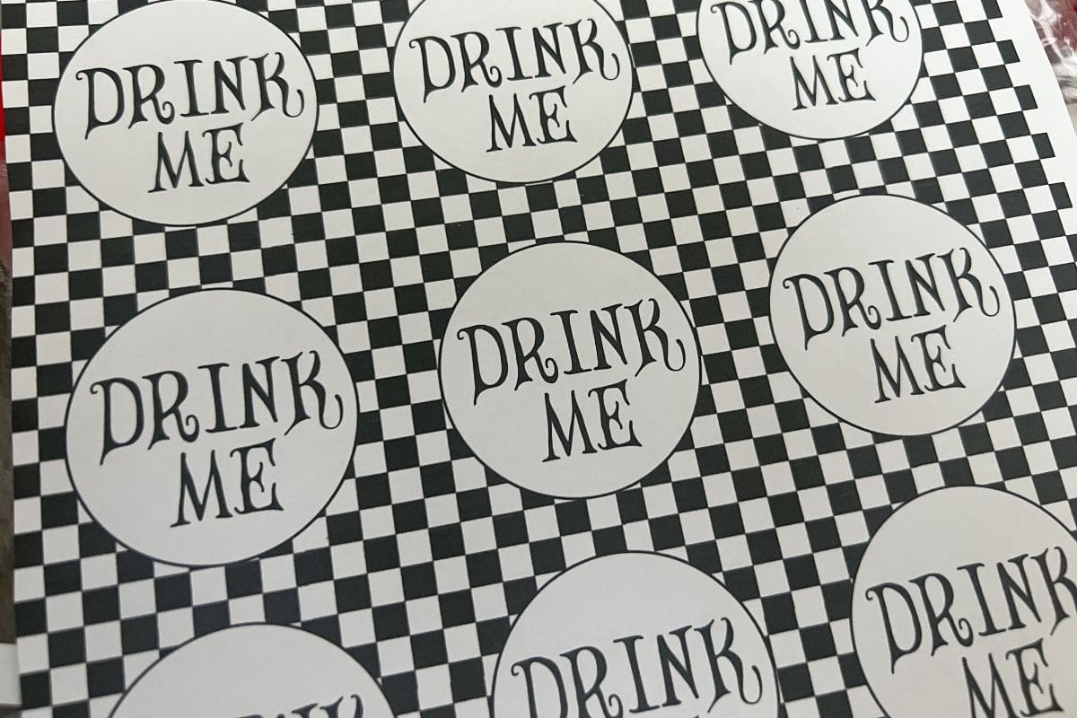 black and white checkerboard adhesive paper with circles that say "Drink Me"