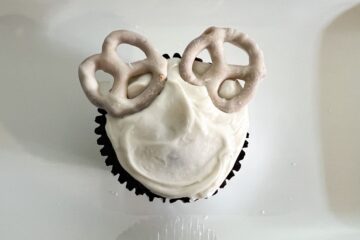 two white fudge covered pretzels near the top of a cupcake to represent polar bear ears