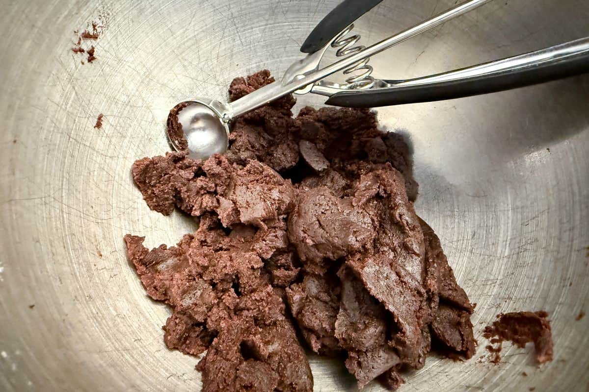 cake pop mixture in a metal mixing bowl with a small dough scoop