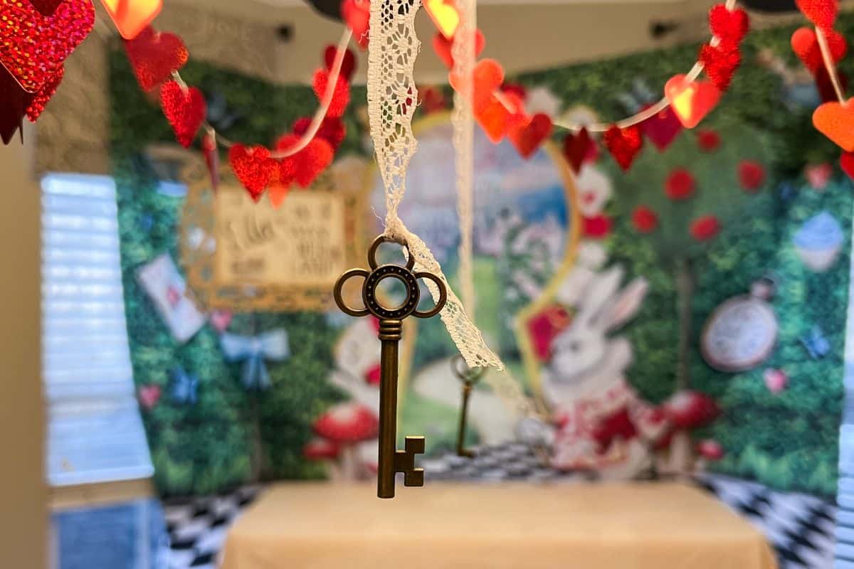 a key hanging from a chandelier with lace ribbon