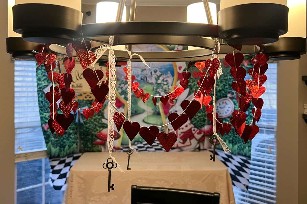 a heart banner and keys hanging from a chandelier with lace ribbon