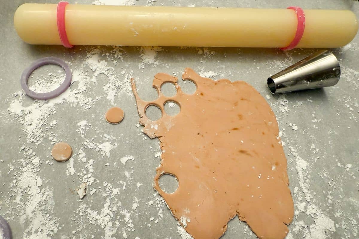 light brown fondant rolled out with a metal piping tip used as a small round cutter