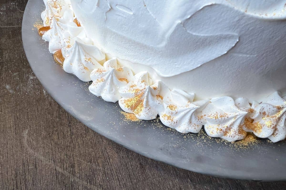 edible gold glitter sprinkled on top of an ice cream cake covered with whipped topping