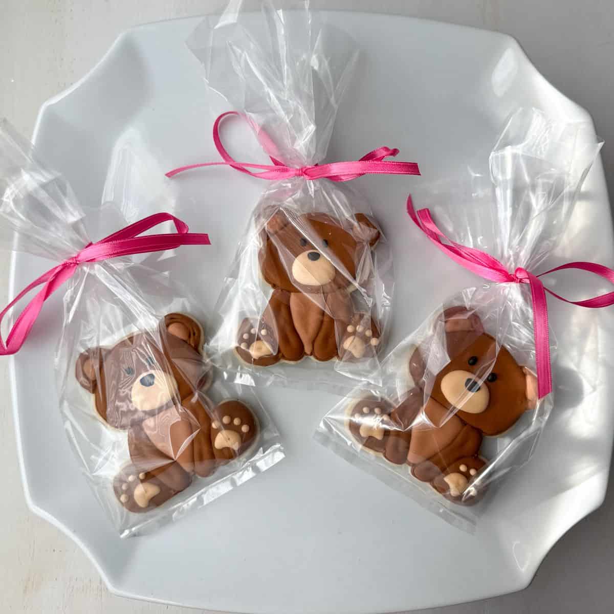 teddy bear cookies packaged in clear treat bags tied with pink ribbon