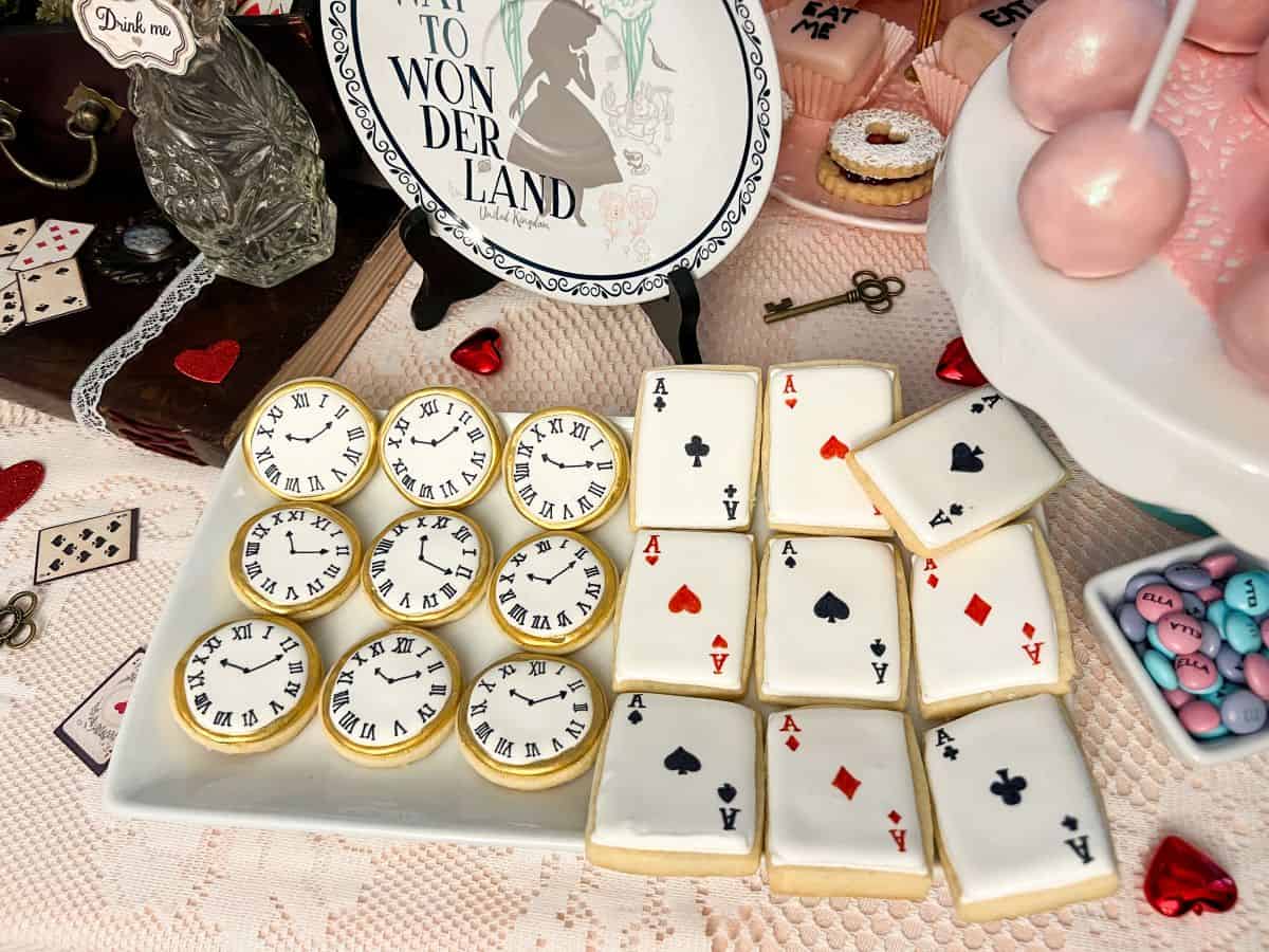 Pocket watch clock cookies and playing card cookies on a white plate