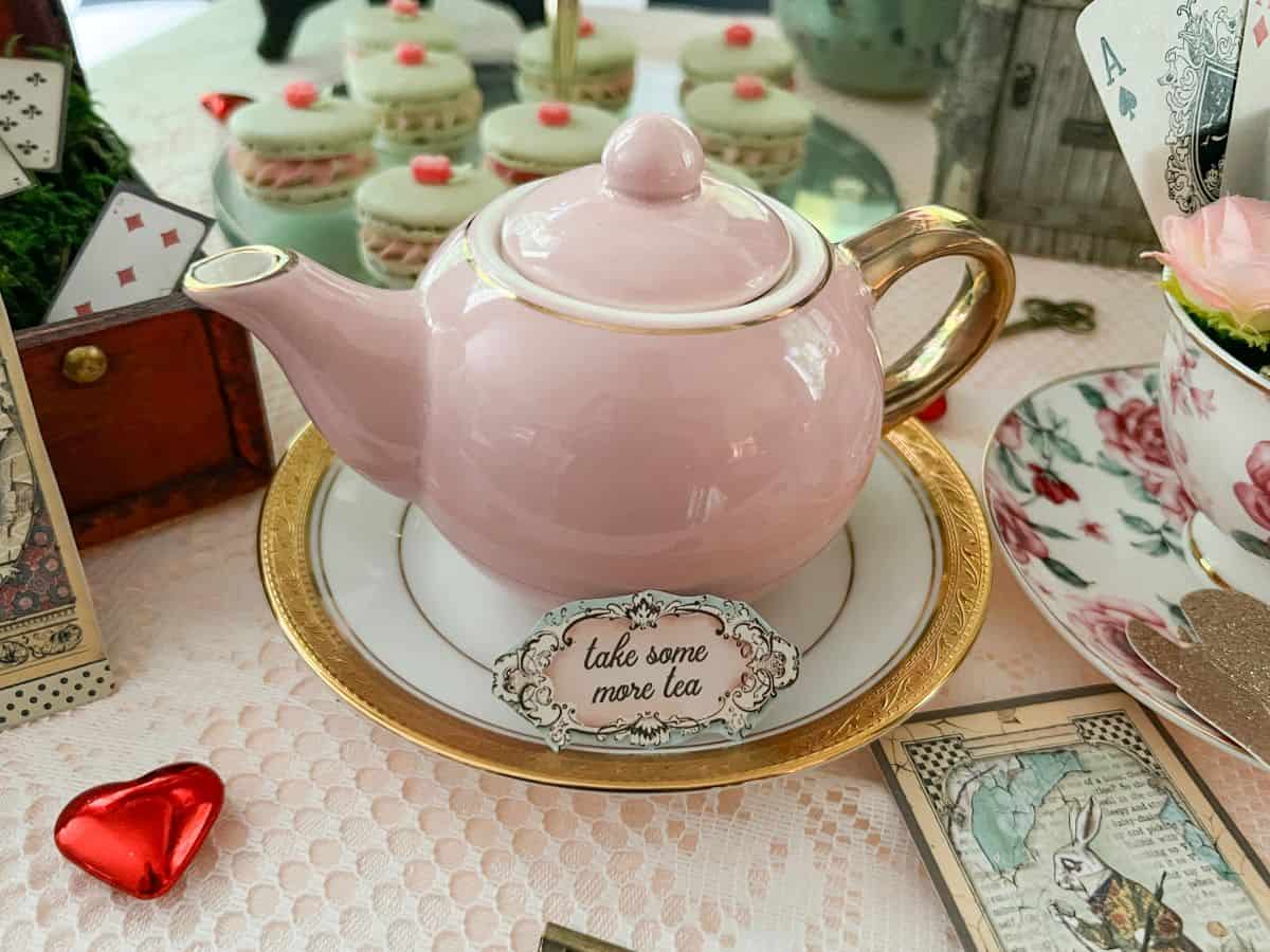 a small pink teapot on a dessert table