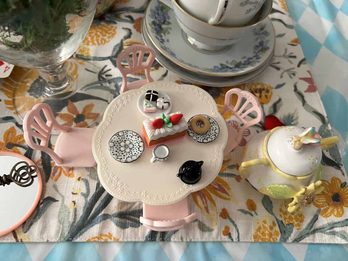 a tiny table and chairs with a tea party set up on it from a Calico Critters set