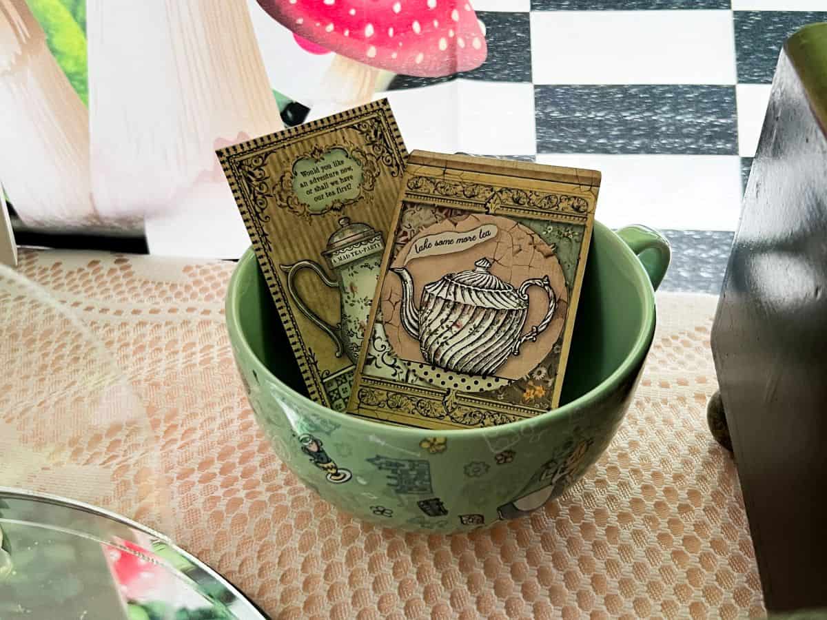 an Alice in Wonderland teacup filled with some Alice in Wonderland vintage cards