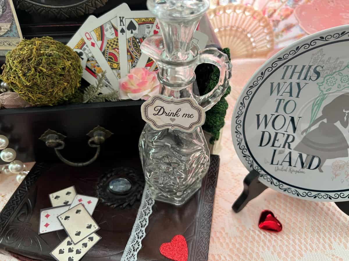 a glass decanter with a sign "drink me" on the front