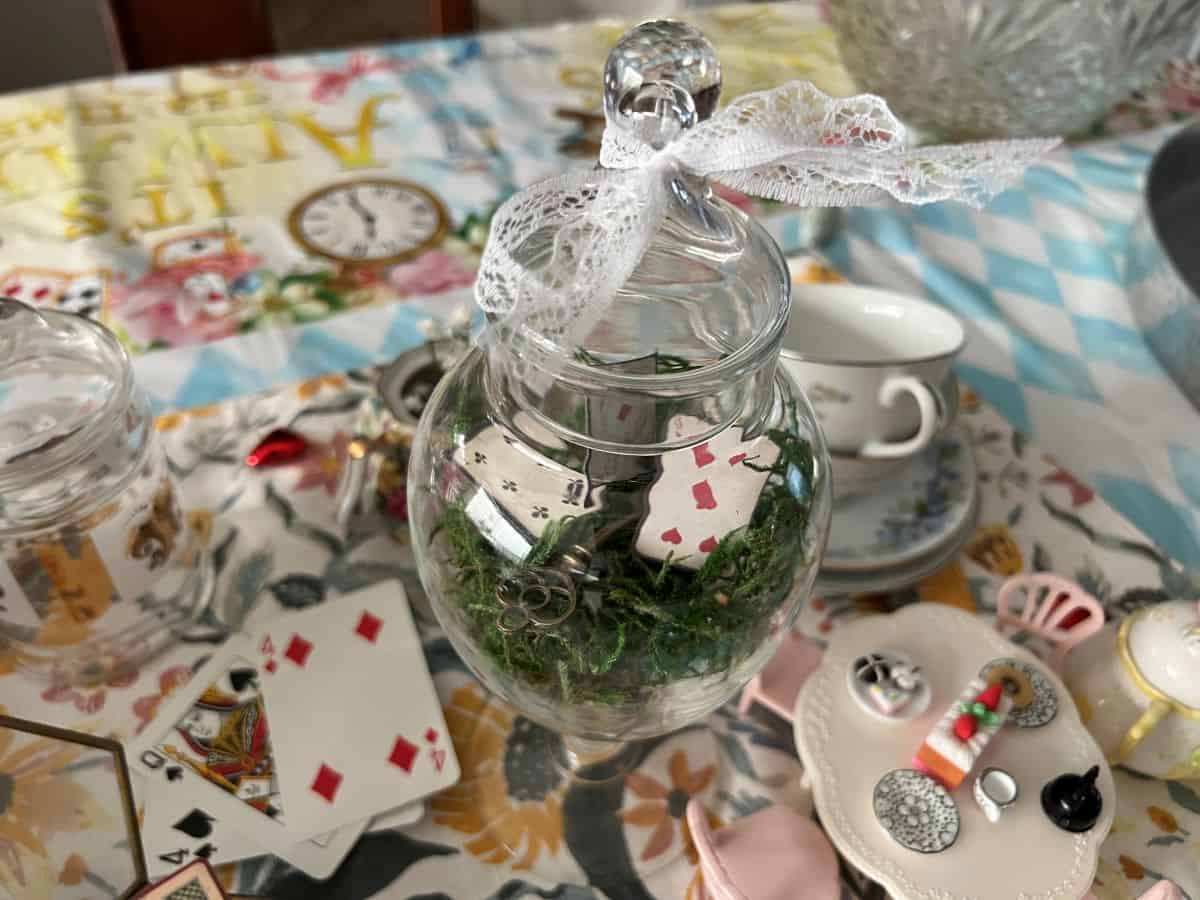 a lidded glass filled with faux moss and cardstock playing cards