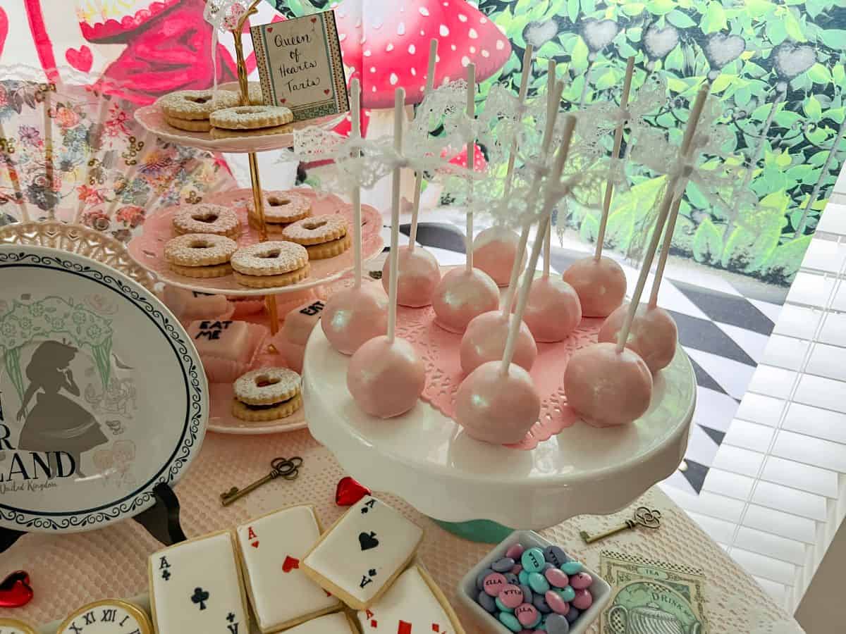 light pink cake pops on a white stand on an Alice in Wonderland dessert table