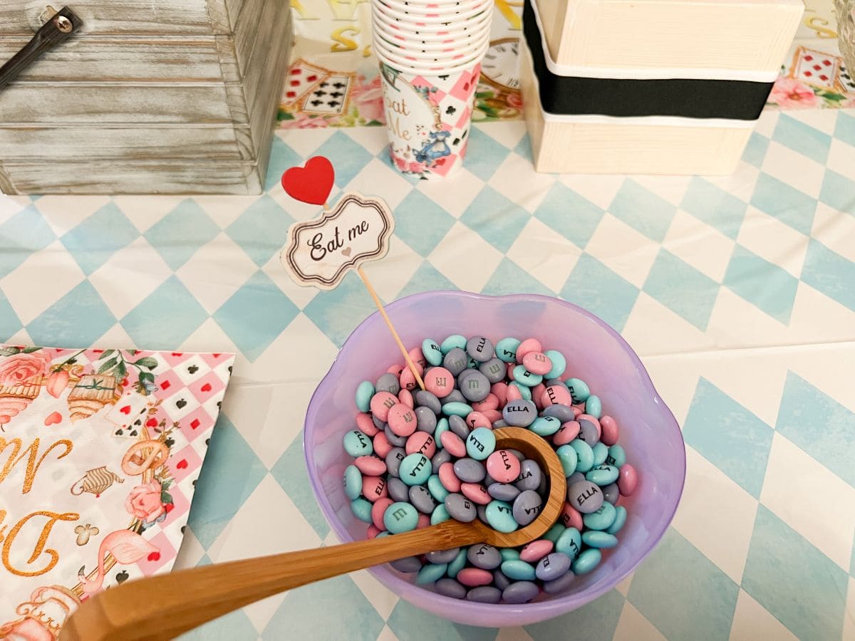 a bowl filled with pastel personalized M&M's and a wooden scoop