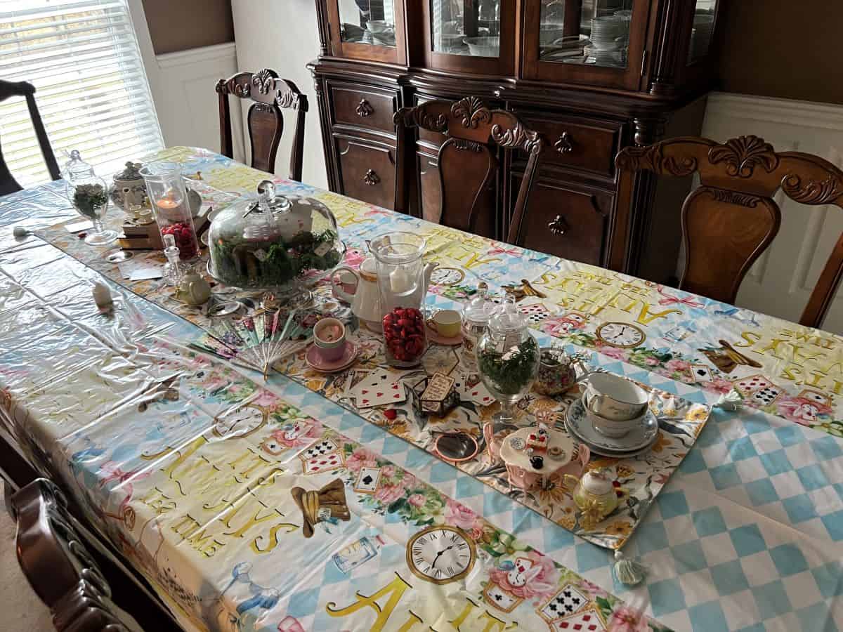 a dining room table with a runner decorated for an Alice in Wonderland Mad Hatter's Tea Party