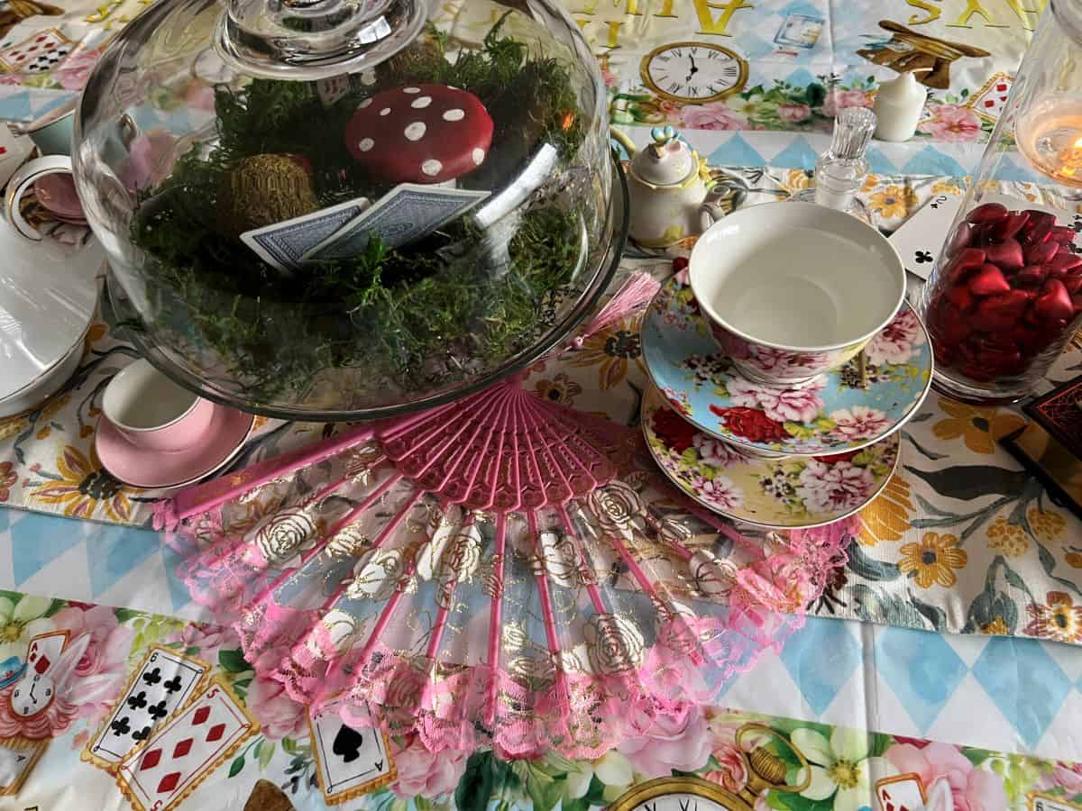 a hand fan splayed on a Mad Hatter's tea party table