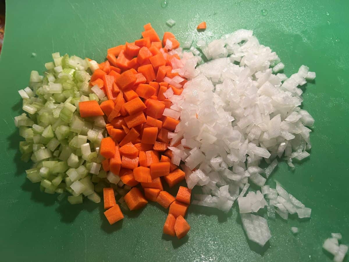 chopped celery, carrots and yellow onion on a green cutting mat