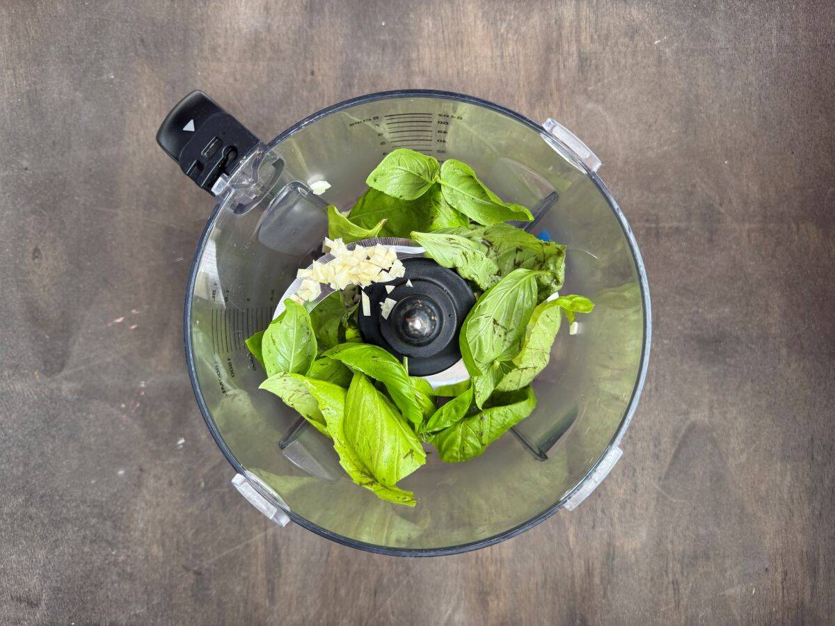 basil leaves and garlic in the bowl of a food processor