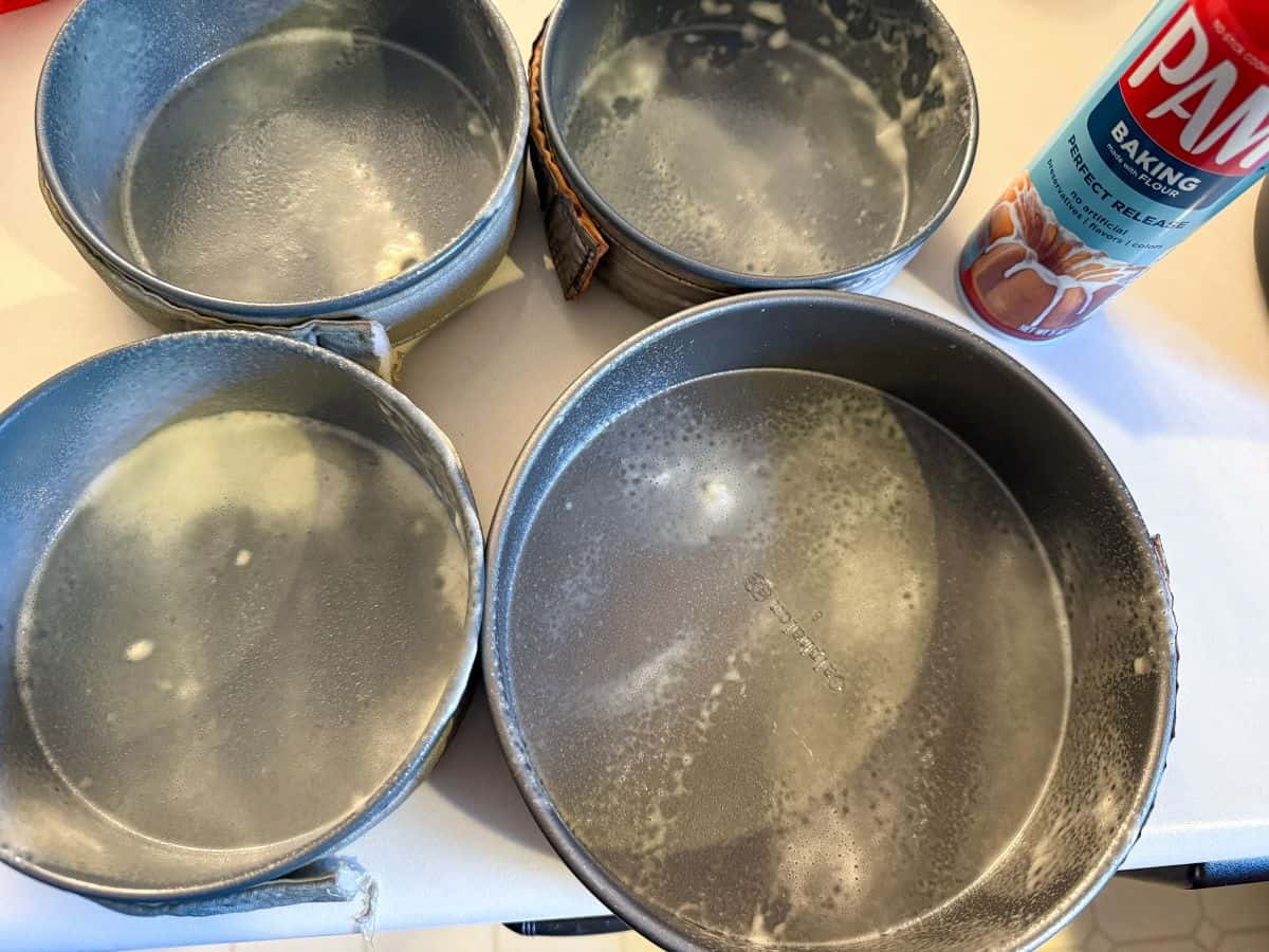 an 8 inch cake pan and three 6 inch cake pans sprayed with nonstick baking spray