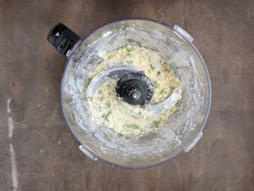 basil garlic tart dough being mixed in the bowl of a food processor