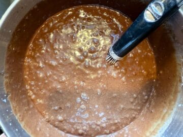 chocolate cake batter in a mixing bowl with a wire whisk in the batter